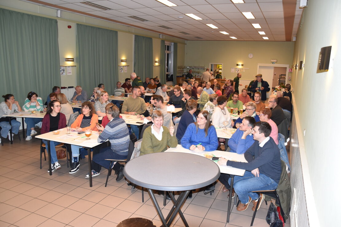 Teams aan lange tafels tijdens de quizavond 2024